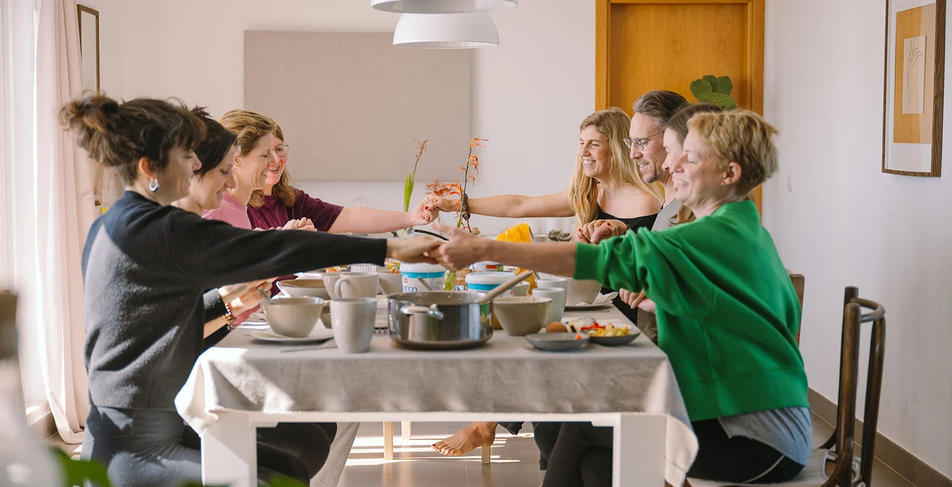 Freunde genießen eine Mahlzeit an einem Tisch, umgeben von Essen und fröhlichen Gesprächen.